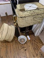 Two lamp bases on floor with loose fabric shades and a white glass bowl shade, power cords visible