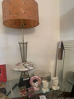 Overview showing lamp, plates, head vases and model houses on glass shelf.