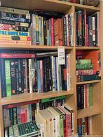 Bookshelves filled with a variety of books by different authors and on different topics, arranged vertically and horizontally in used condition.