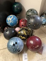 Photo showing the full collection of 10 bowling balls with various colors and designs, standing on the floor