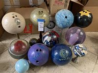 13 bowling balls on display showing various colors, brands, and designs including glitter and personalized engravings.