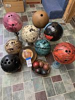 Overview of 10 bowling balls in various colors, some on display stands, showing different wear levels and finger hole configurations.