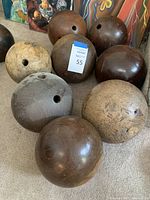 Eight wooden bowling balls on carpet, with visible finger holes and varying wood finishes