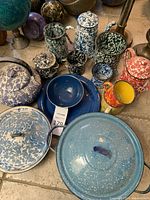 Overview photo showing various enamel camping cookware including teapot, pots, pans, kettles, and cups in marbled and speckled enamel finishes in various colors