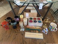 Wide view showing entire collection of candle holders, candles, and candelabra on wooden floor.