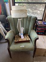 Overall view of fabric armchair with lamp and wooden case