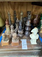 Wide shot showing entire set of large stone chess pieces and two ceramic music box busts on wooden bases in used condition