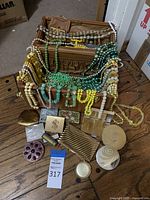 Overall lot of costume jewelry including beaded necklaces, belt, compact cases, small purses, and travel case showing items arranged for visual inventory.