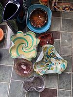 Seven freeform and shaped bowls plus two small dishes on tiled floor