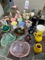Overview of all miniature glass and ceramic decorative vases, bowls, and dishes arranged on tile surface