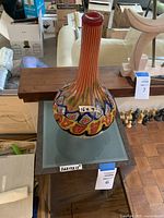 Photo showing top view of decorative vase on the brown glass-top stand with visible size labels.