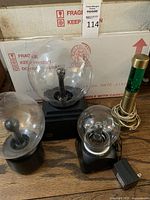 Three plasma globe lamps on black bases and one green lava lamp on wooden floor