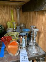 Overview of all 15 pieces grouped on a wooden shelf: assorted vases, candlestick holders, plate, bowl, mirrored holder, decanter.