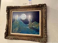 Front view of framed artwork showing woman, castle, and full moon at night, marked with lot number and dimensions