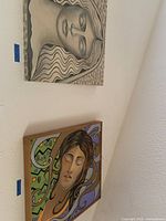 Wall-mounted art pieces: framed black and white portrait and colorful canvas art of women.