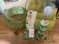 Two acrylic block table lamps in green and clear layers alongside two round drum shade frames with swirl patterns