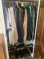 Closet view showing various men’s sweaters, jackets and shoes on the floor including dress, casual, and athletic shoes in size 13 wide.