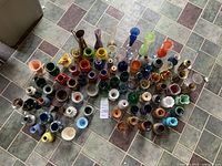 Overhead image showing entire collection of various small vases arranged on floor tiles, displaying variety of colors and materials