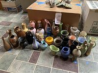 Overview of 22 miniature vases on tiled floor showing front and back rows