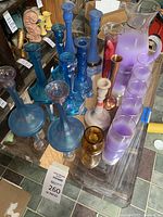 Overview of all items on the table including purple glass pitcher, glasses, blue candlesticks, and decorative glass pieces