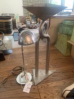 Wide view showing the tall silver tone lamp with twisted metal design and conical shade, alongside smaller adjustable shade lamp