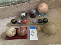 Full view of all decorative balls arranged on carpet and stands, showing size and color variety.