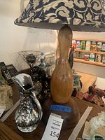 Wooden bowling pin shaped table lamp, close-up of base and fabric shade, showing brown and beige floral pattern
