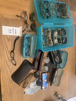 Overhead view of multiple eyeglasses and sunglasses frames in plastic storage cases alongside loose frames and cases