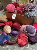 Full view of the vintage hats collection showing various colors and styles piled in front of a cardboard box.