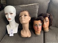 Four female mannequin heads displayed on couch.