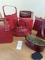 Group shot of seven red-tone vintage purses and clutches on wooden floor