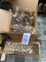Box containing multiple Pyrex glass flasks, mostly round bottom with multiple necks, and a separate box filled with small lab parts.
