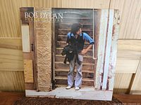 Front cover of Bob Dylan Street Legal LP, shows Bob Dylan posed on stairs outdoors, album title and artist name visible.