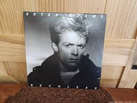 Front cover of Bryan Adams Reckless album showing grayscale close-up portrait of Bryan Adams with white lettering.