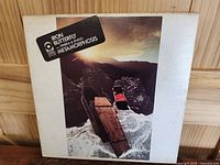 Front cover of the Metamorphosis gatefold album showing coffin imagery on the sea with mountainous background.