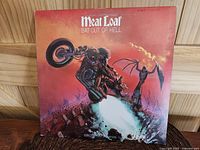 Front cover of the vinyl album showing the iconic motorcycle and bat figure in fiery scene. Album title 'Meat Loaf - Bat Out Of Hell' at top.