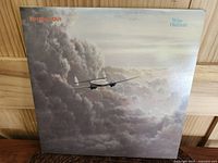 Front cover of the Mike Oldfield 'Five Miles Out' LP showing an airplane flying through clouds with album title and artist name.