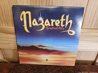 Front cover of Nazareth Greatest Hits vinyl LP showing stylized sunset design with band logo and title.