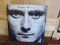 Front cover showing close-up black and white portrait of Phil Collins, handwritten 'Face Value Phil Collins' at top, slight edge wear visible.