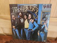 Front cover of $ Rockets 'Turn Up The Radio' album showing band members posed outdoors, with the album title and band name.