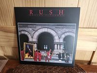 Front cover artwork of Rush Moving Pictures album showing figures carrying framed paintings on stone building steps