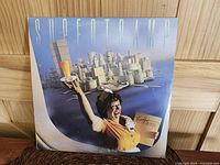 Front cover of the vinyl record showing waitress holding tray with orange juice and menu titled 'Breakfast in America' with stylized urban background