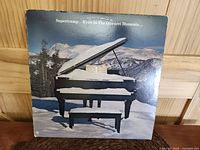 Front cover of album featuring grand piano in snow with visible edge and ring wear.