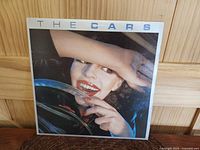 Front cover of The Cars LP featuring a woman smiling behind a car steering wheel.