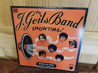 Front cover of the 1982 EMI America club edition vinyl LP album 'Showtime' by The J. Geils Band showing orange background, band member illustrations, and album title text.