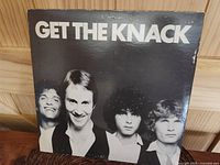Front cover of The Knack Get The Knack album showing band members smiling in black and white photo with some edge and surface wear visible.