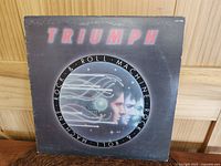 Front cover of the LP showing title and artwork of faces and circuitry on dark background with edge and shelf wear.