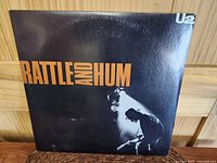 Front cover of U2 Rattle and Hum album showing title in orange and black silhouette of the band.