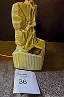 Side view of green ceramic TV lamp planter showing leaf design and rectangular ribbed base