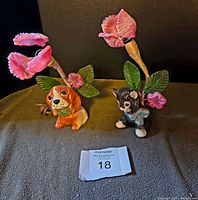 Front view of both ceramic puppy and kitten nursery lamps facing forward with pink molded glass flowers and green leaves.